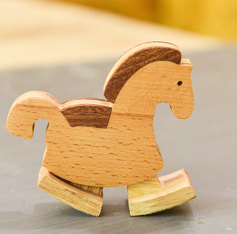 Wooden horse toy on a reflective surface with a blurred background