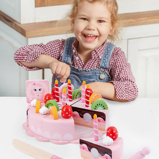 Child playing with a toy cake set on a white surface
