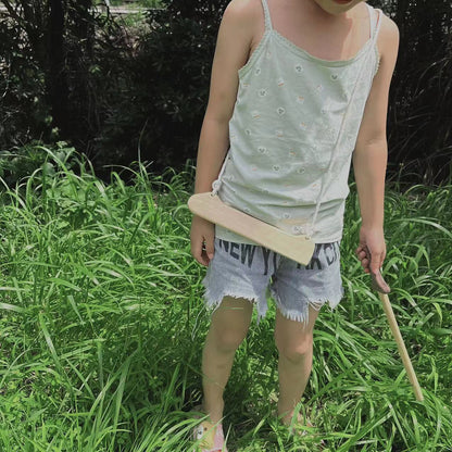 Child outdoors playing with handcrafted Montessori wooden toy sword, eco-friendly and non-toxic.