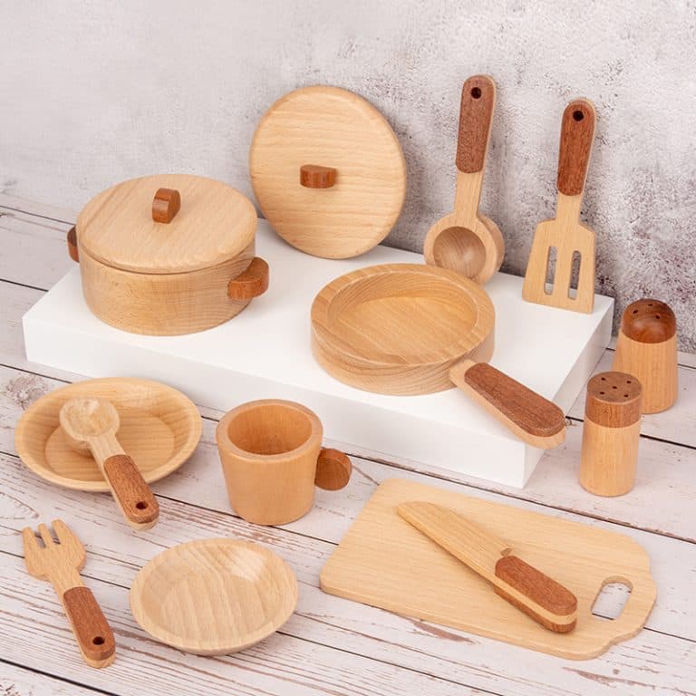 Wooden kitchen utensils and cookware set on a wooden surface with a light gray background.