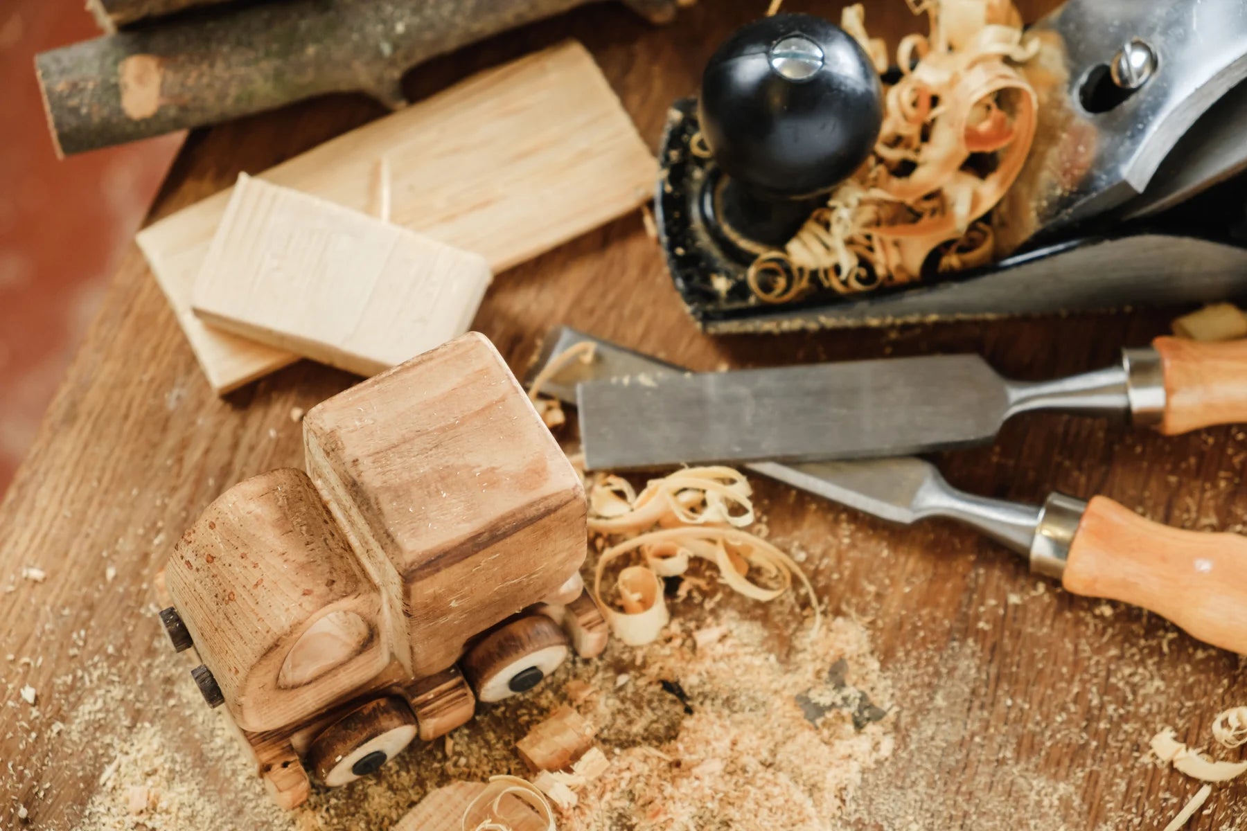 Wooden toy truck on a wooden surface with chisels and a mallet.