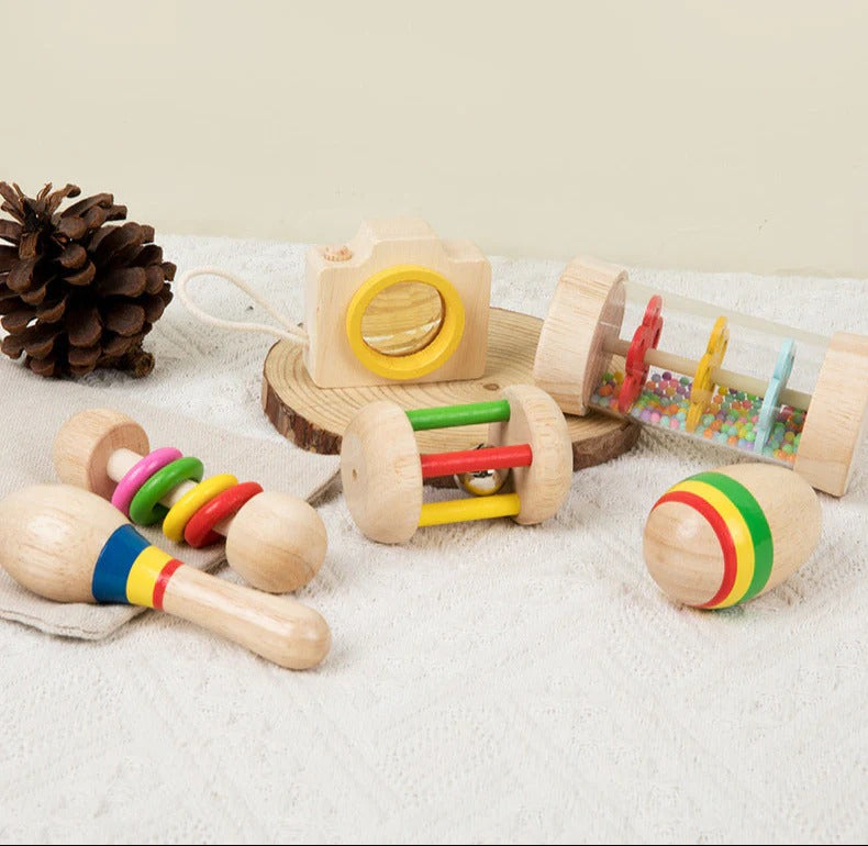 Set of wooden toys for infants on a soft surface with a pine cone.