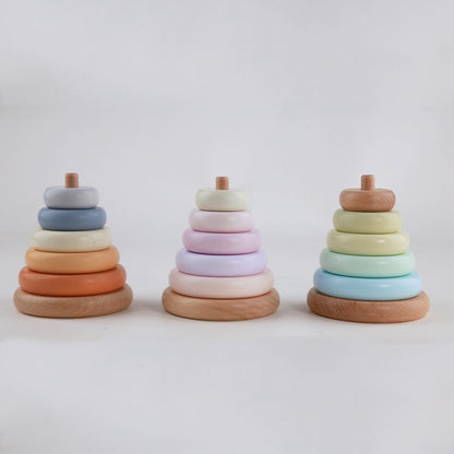 Three wooden ring stacking toys in pastel colors on a white background