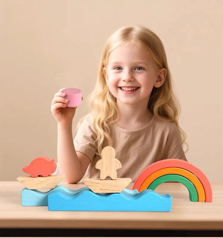 Smiling child playing with Montessori rainbow wooden toy blocks on a table