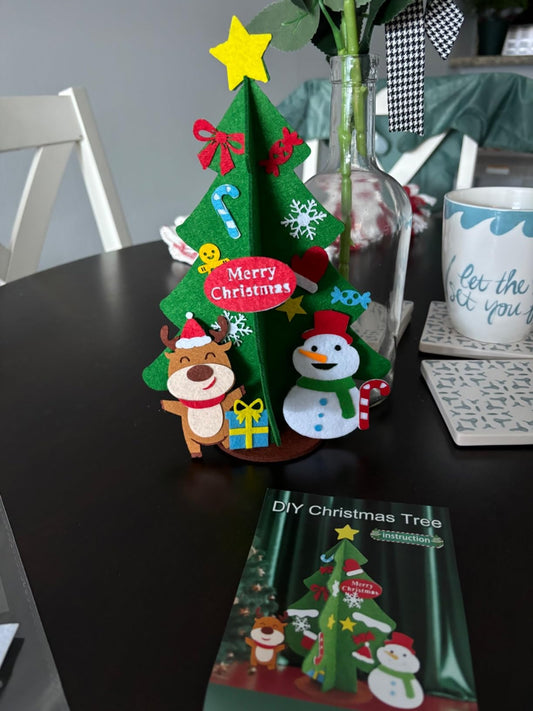 Colorful DIY Christmas tree decoration on a table with a vase and mug in the background.