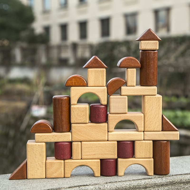 Wooden building blocks stacked in a tower with a blurred outdoor background