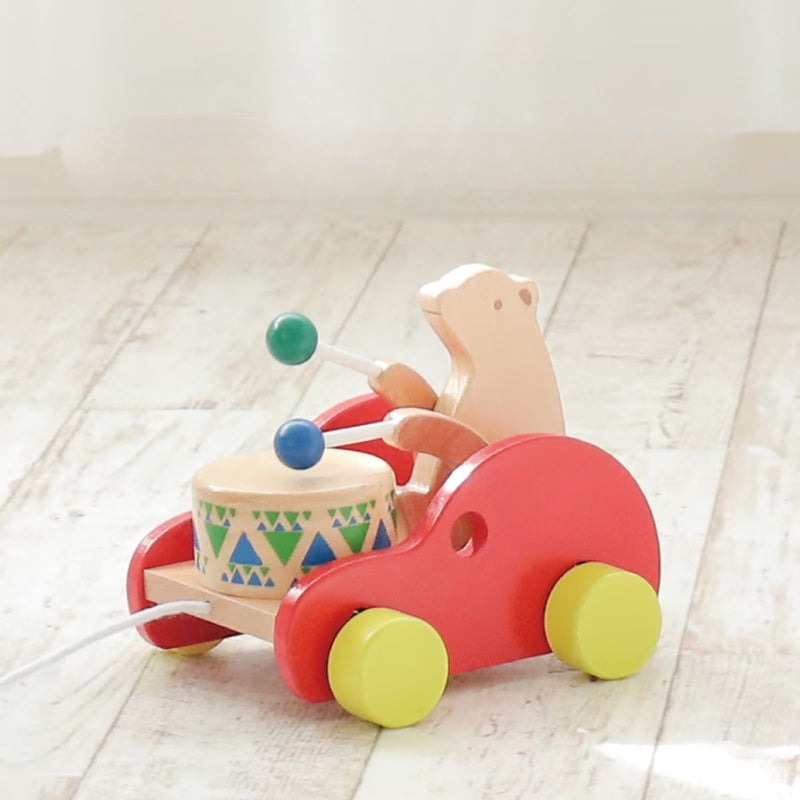 Handcrafted Montessori wooden bear drum pull toy with red wheels on light wood floor