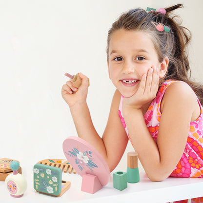 Smiling girl playing with Montessori wooden kids makeup play set, eco-friendly and handcrafted.