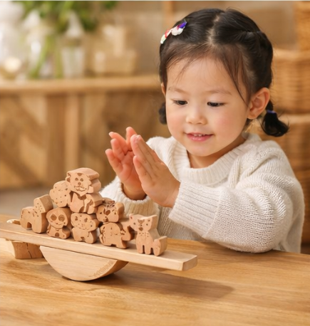 Toddler playing with handcrafted wooden animal balance toy on table, Montessori eco-friendly play