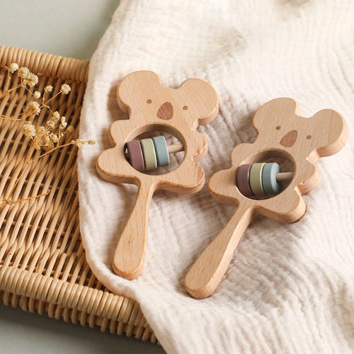 Two wooden bear-shaped teething toys with colorful beads on a textured surface.