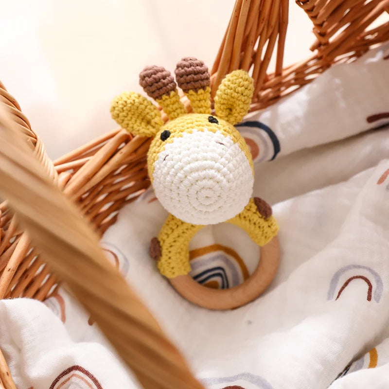 Crocheted giraffe rattle toy in a wicker basket with a soft blanket underneath
