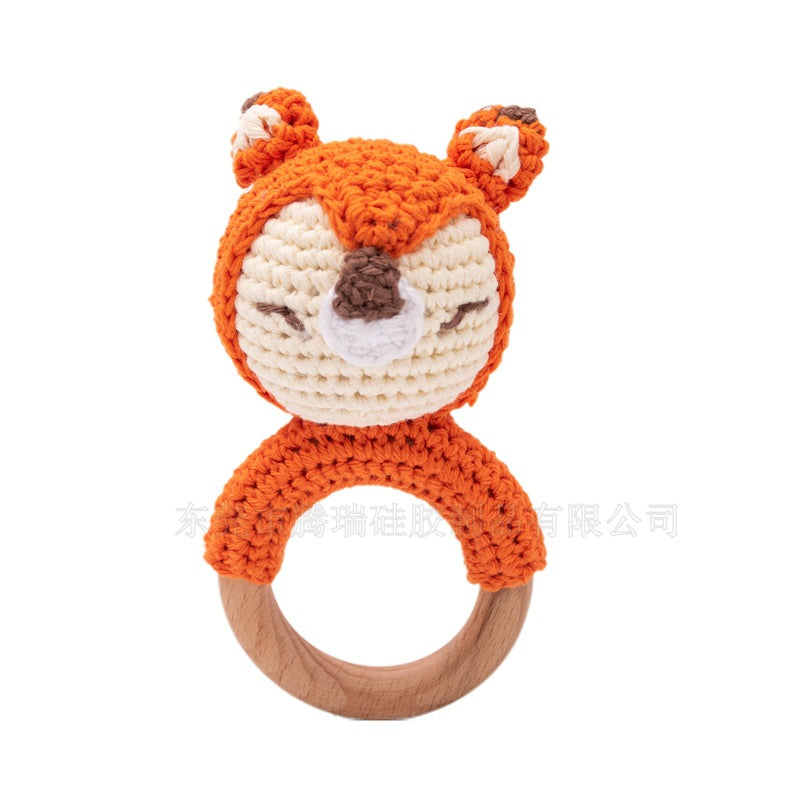 Crocheted fox rattle with wooden ring on a white background