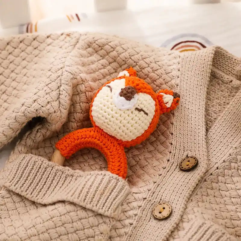 a wooden fox rattle toy on a textured beige fabric cloth