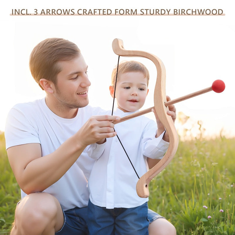 Man and child holding a wooden bow and arrow set in a grassy field.