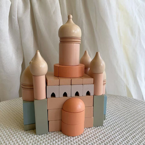 Toy castle made of interlocking blocks on a textured surface with a white curtain background