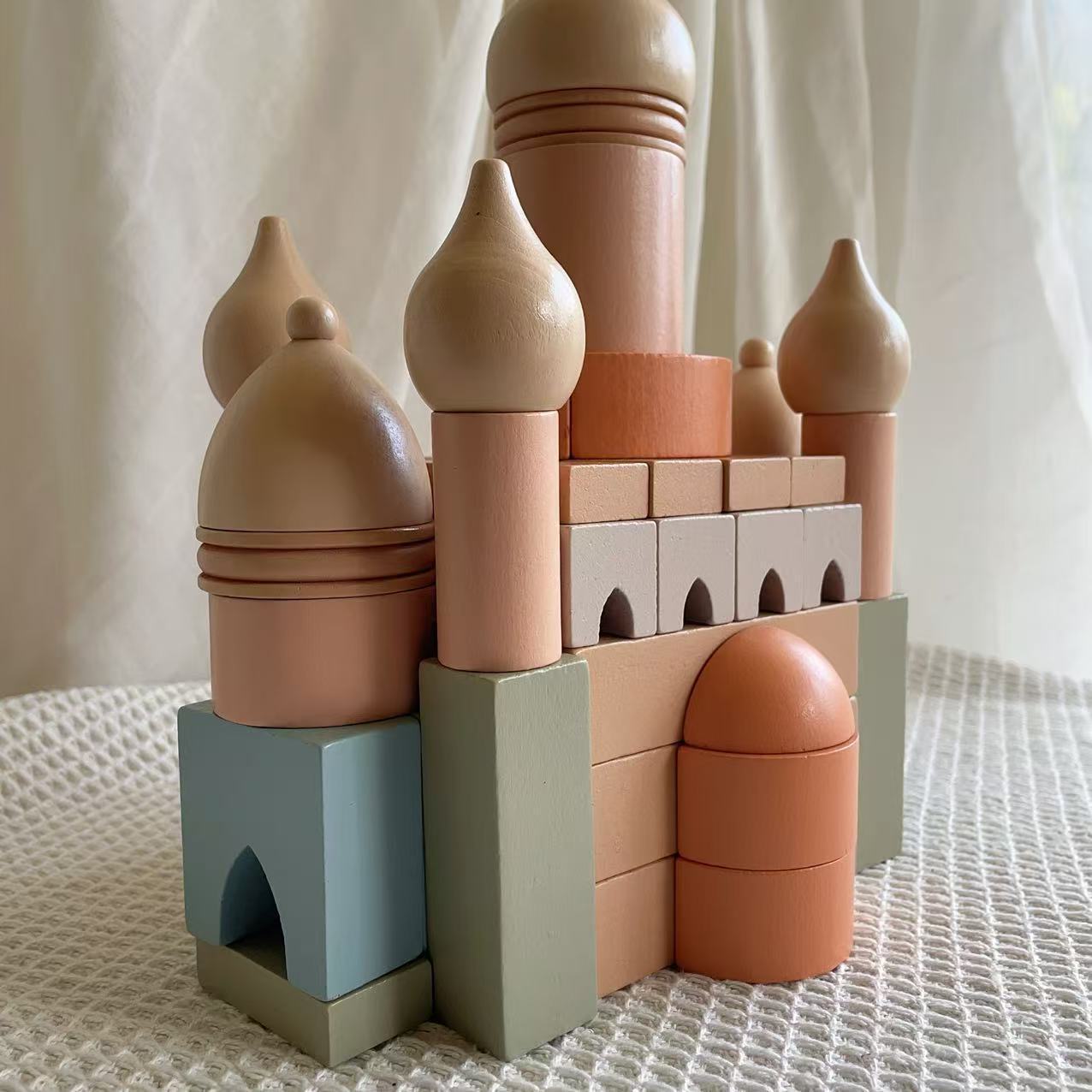 Colorful toy castle made of interlocking blocks on a textured surface with a neutral background