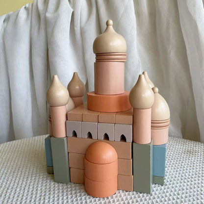 Toy castle made of colorful building blocks on a textured surface with a white curtain background