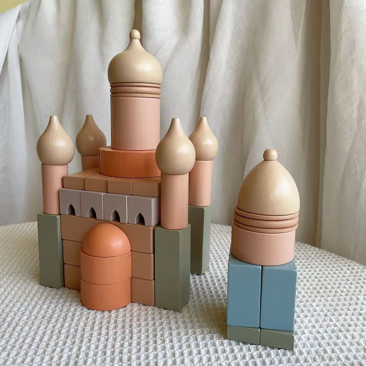 Colorful toy castle made of interlocking blocks on a textured surface with a neutral background