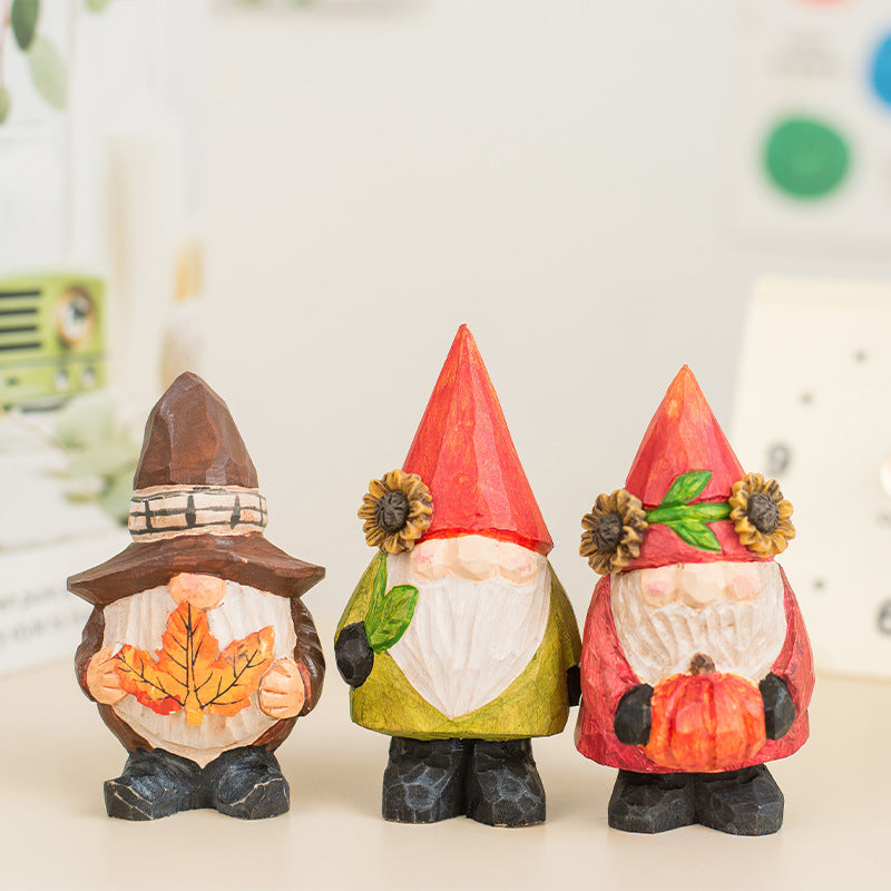 Three gnome figurines with autumn-themed hats and accessories on a light background