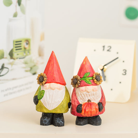 Two small garden gnomes with red hats and sunflower decorations on a blurred background.