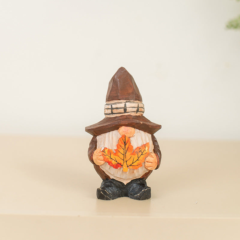 Gnome figurine holding autumn leaves on a beige surface with a white background