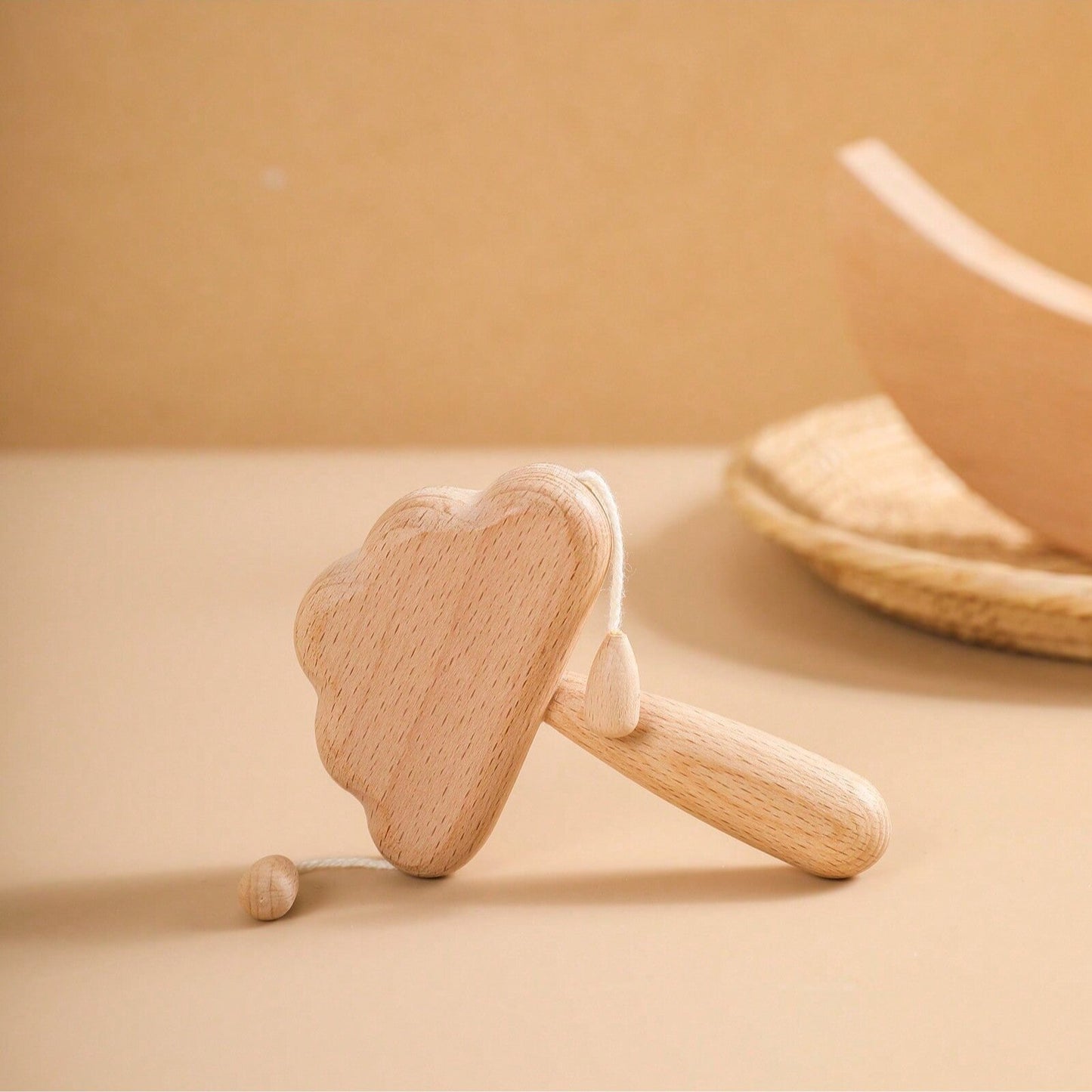 Wooden cloud-shaped rattle on a beige surface with a soft focus background