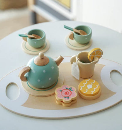 Wooden toy tea set with teapot, cups, and cookies on a white surface