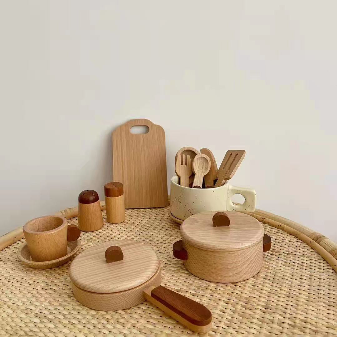 Set of wooden kitchen utensils and containers on a woven surface with a neutral background