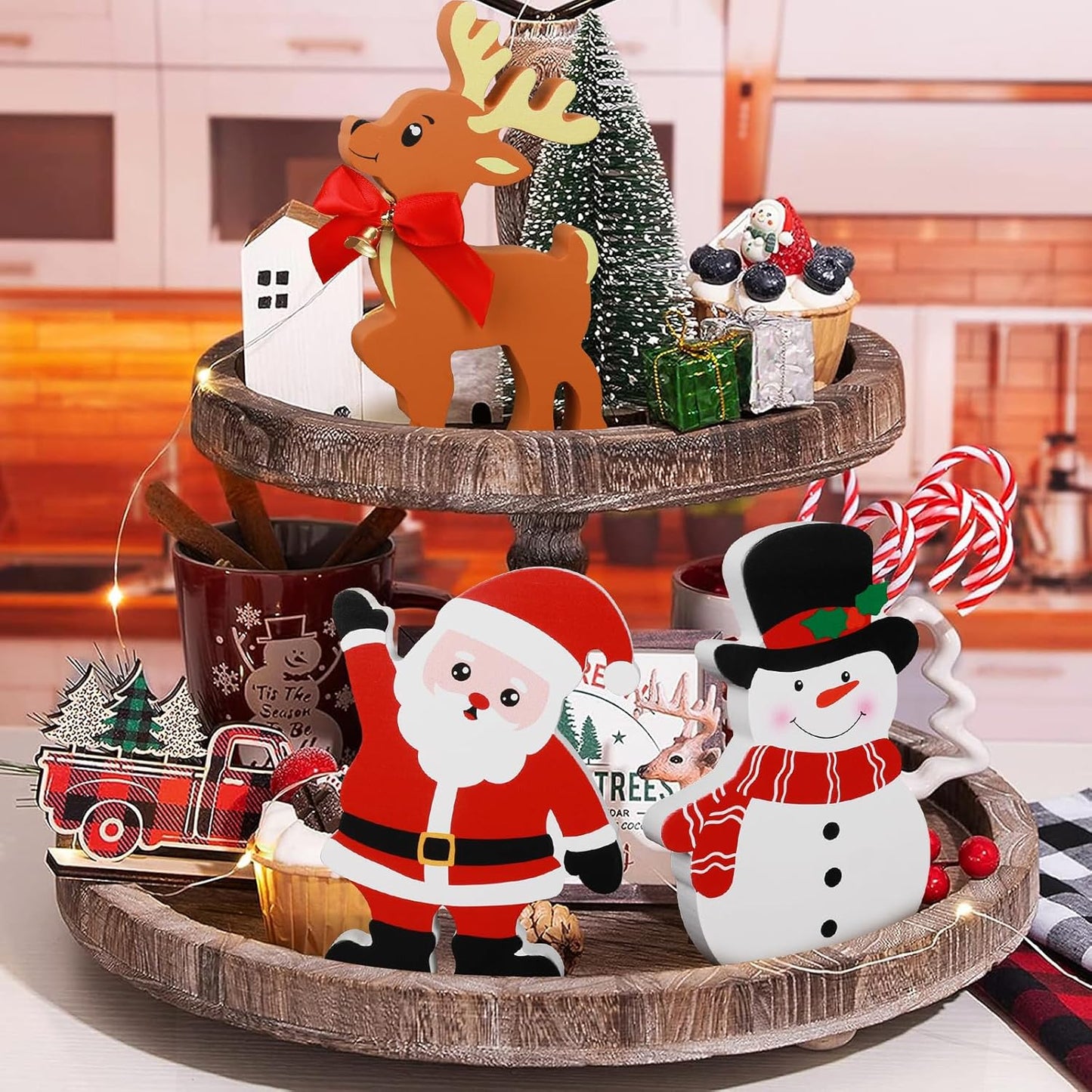 Decorative tiered tray with Christmas-themed figurines and ornaments on a kitchen counter.