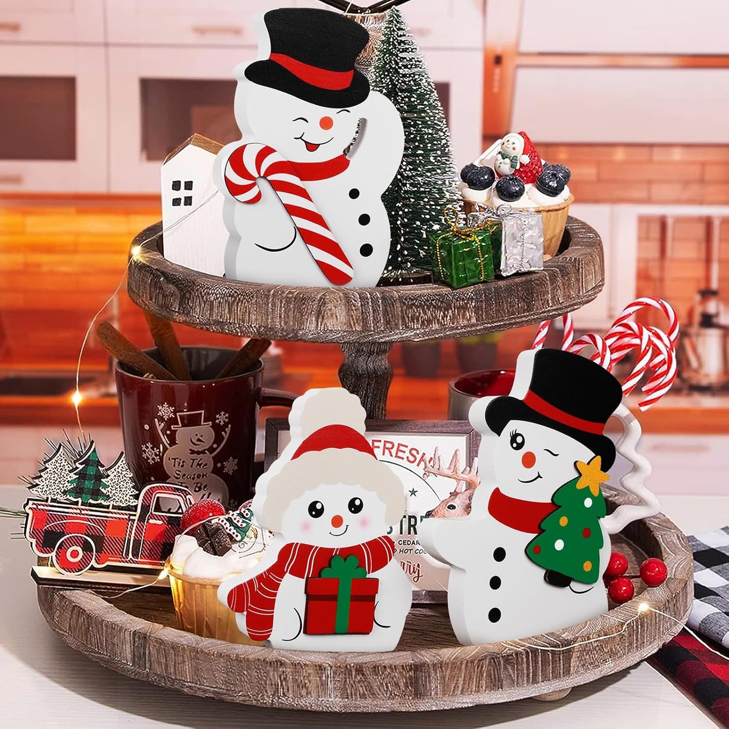 Decorative Christmas tiered tray with snowmen, trees, and a truck on a kitchen counter.