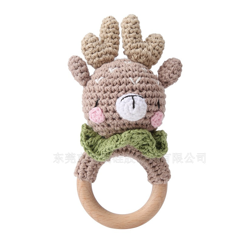 Crocheted deer baby rattle with wooden ring on a white background