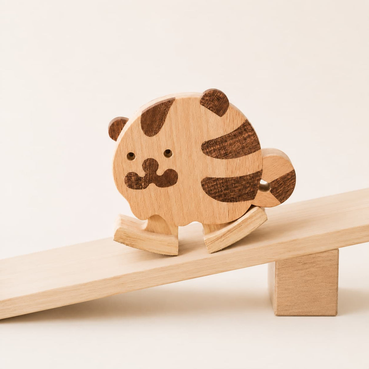 Gravity-powered wooden tiger ramp walker toy stepping down a gentle wooden ramp