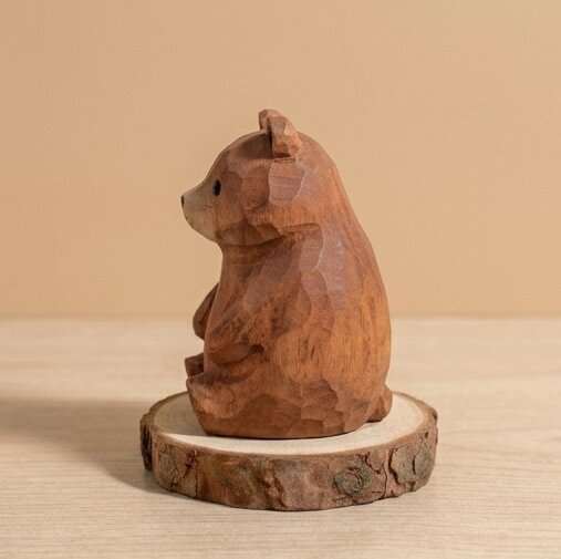 Wooden bear figurine on a wooden base against a beige background
