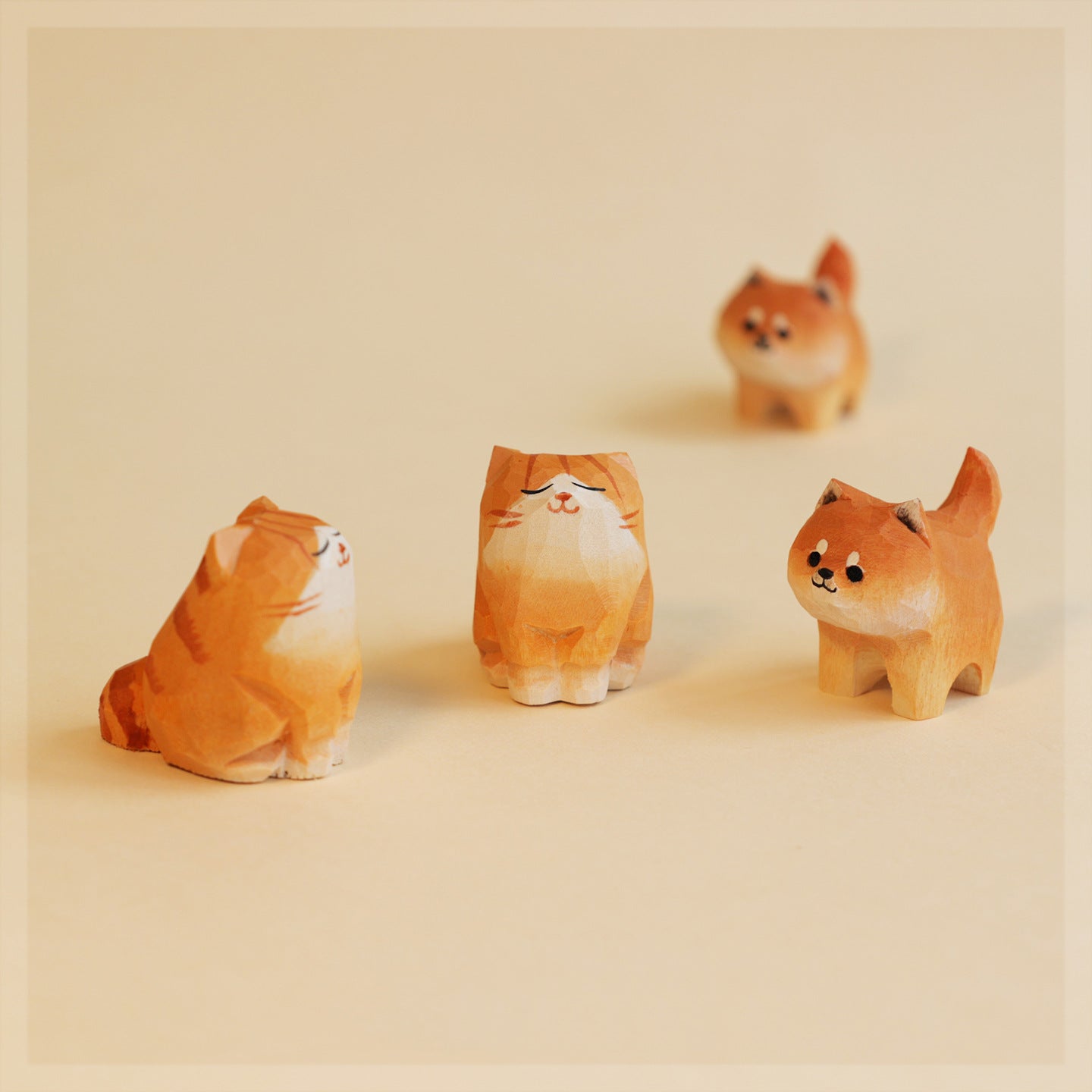 Four small figurines of cats and dogs on a beige background