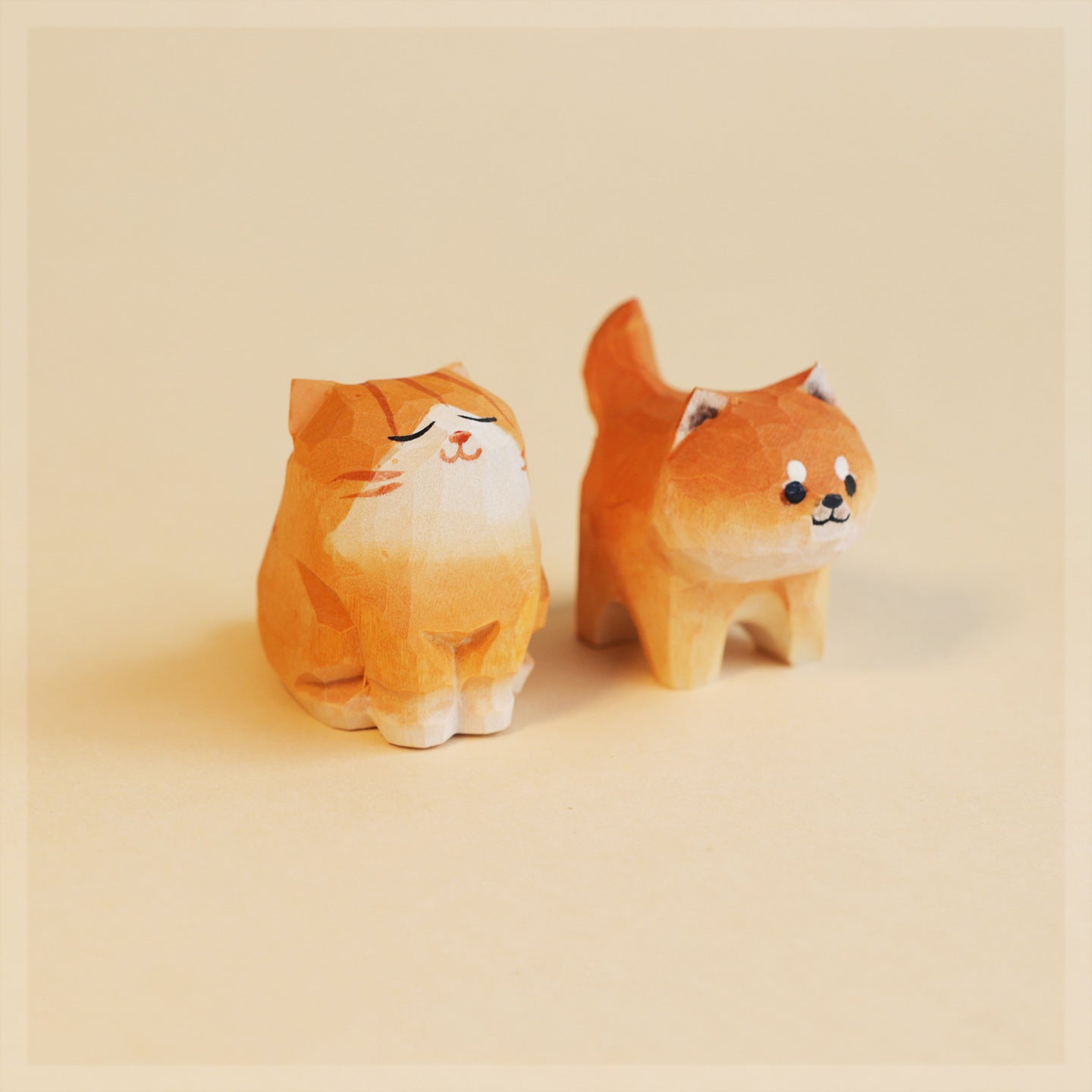 Two plush toys shaped as a cat and a dog on a beige background