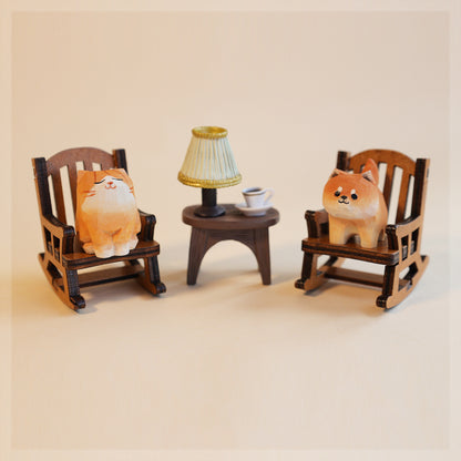 Two plush toys resembling dogs on wooden chairs with a small table and lamp in the center.