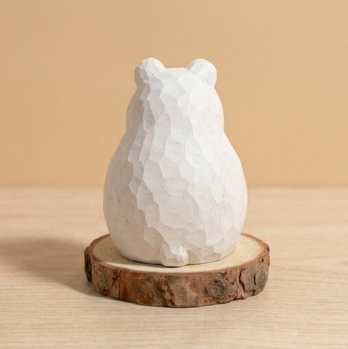 White stone bear figurine on a wooden base against a beige background