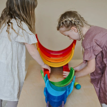 Two children playing with a colorful stacking toy on a beige surface.