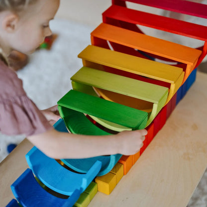 Child playing with a colorful wooden toy on a wooden surface