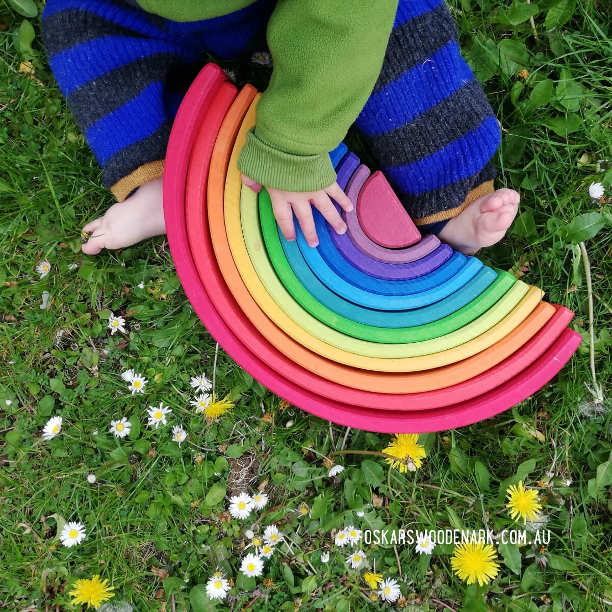 Child playing with a colorful wooden toy on grass