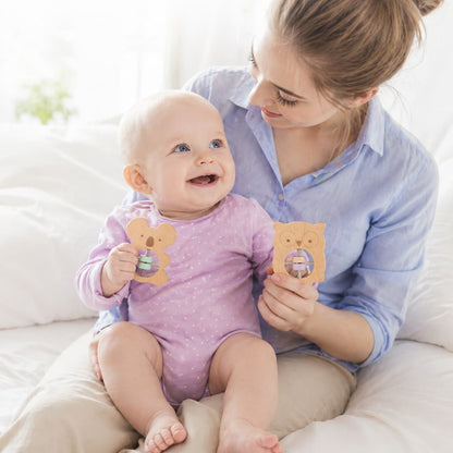 A mother and baby bonding while playing with koala and owl-shaped wooden rattles, featuring an easy-to-grip design for Montessori sensory exploration and early motor skill development.