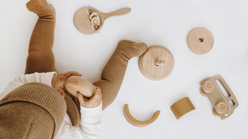 Child playing with wooden toys on a white surface