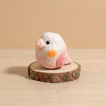 Handcrafted pink and white wooden lovebird toy with orange cheek, geometric low-poly bird figurine eco-friendly natural wood toy for toddlers on rustic wood slice