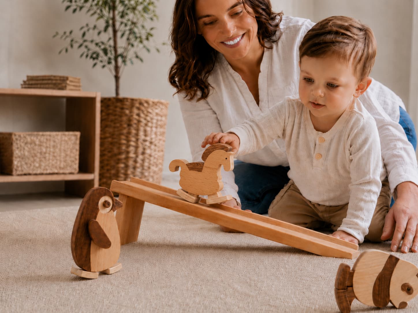 Toddler enjoying screen-free wooden ramp walker toys with a parent in a warm playroom setting.