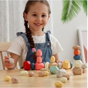 Smiling child playing with colorful Montessori wooden stacking stones at a table.