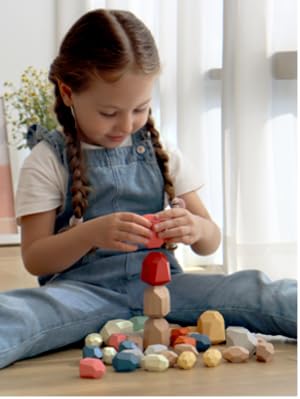 Child playing with colorful wooden blocks on a wooden floor.