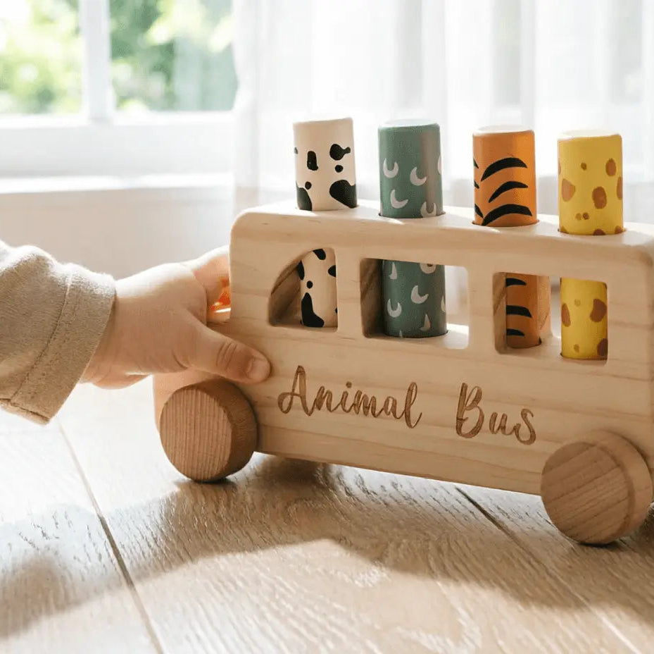 natural wooden animal bus toy from the side showing four animal cylinders and smooth beech wood wheels