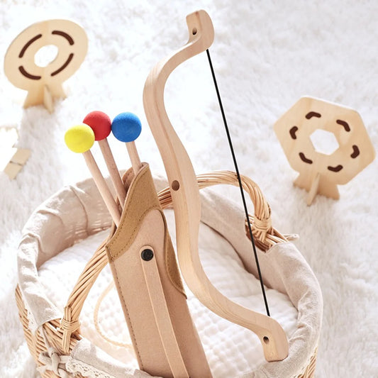 Wooden toy bow and arrow set on a white textured background
