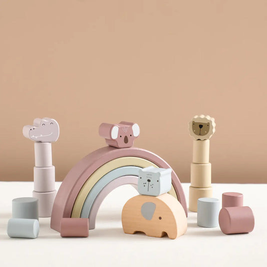 Set of pastel-colored wooden toys including a rainbow arch and animal shapes on a beige background.