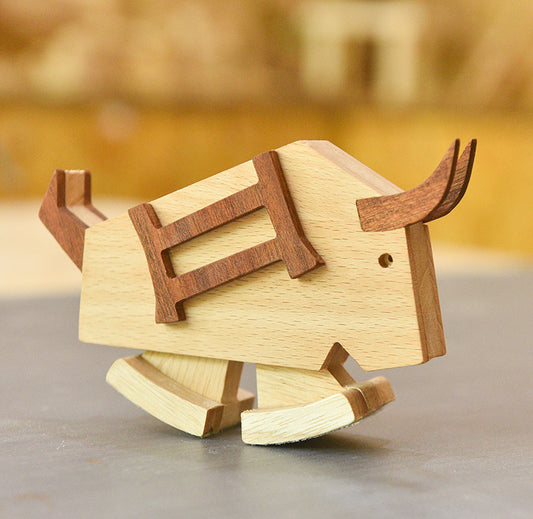 Wooden bull figurine on a reflective surface with a blurred background